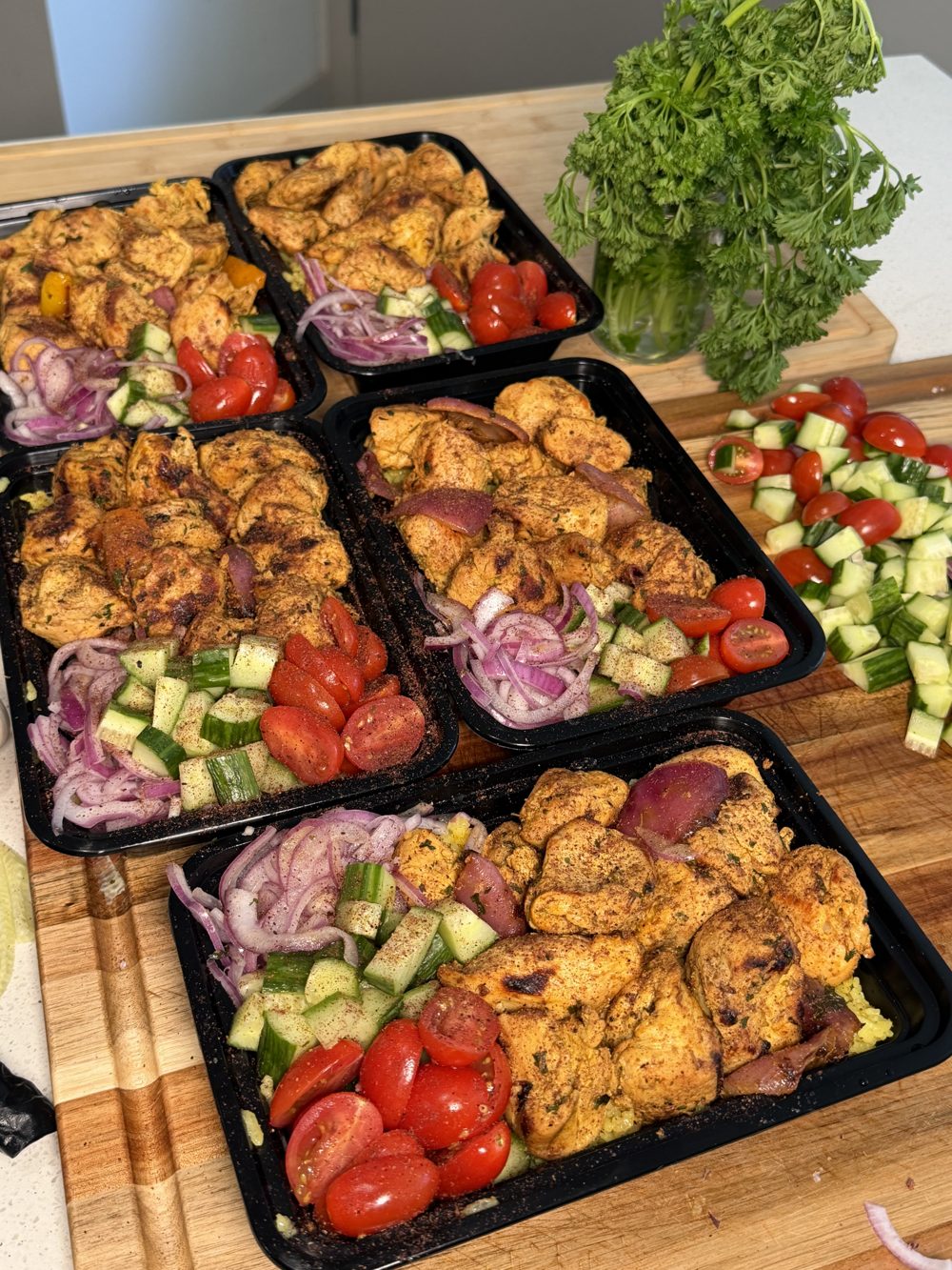 Greek chicken bowls with cucumber tomato salad in meal prep containers